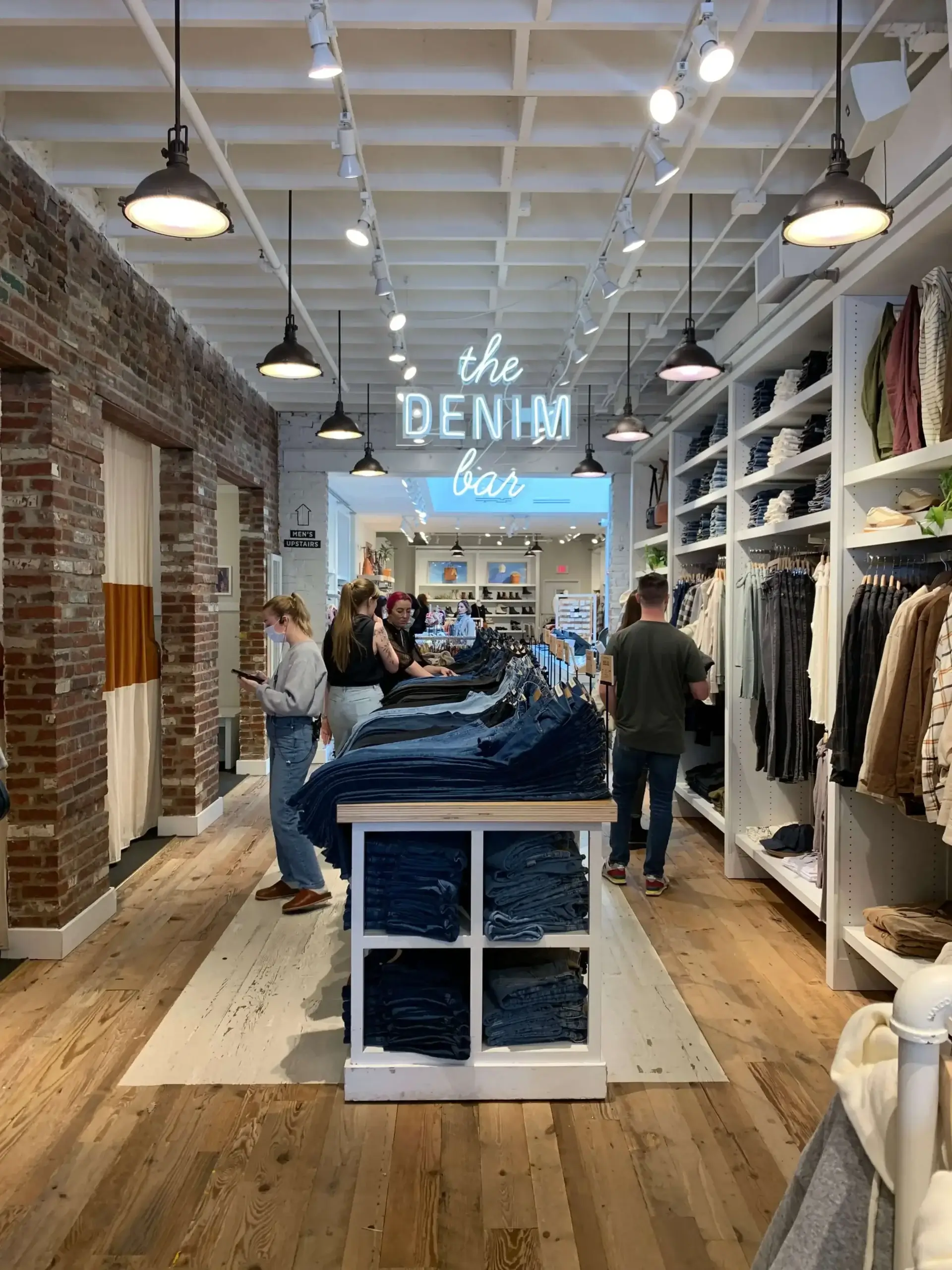 Inside of a Madewell retail store showing denim and shoppers - brands like everlane