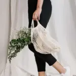 woman wearing sustainable clothing and carrying reusable tote bag