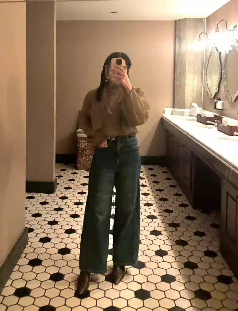 woman in green blouse and jeans rented from Nuuly clothing rentals