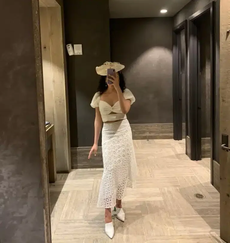 woman in white skirt and top rented from Nuuly with fascinator on head