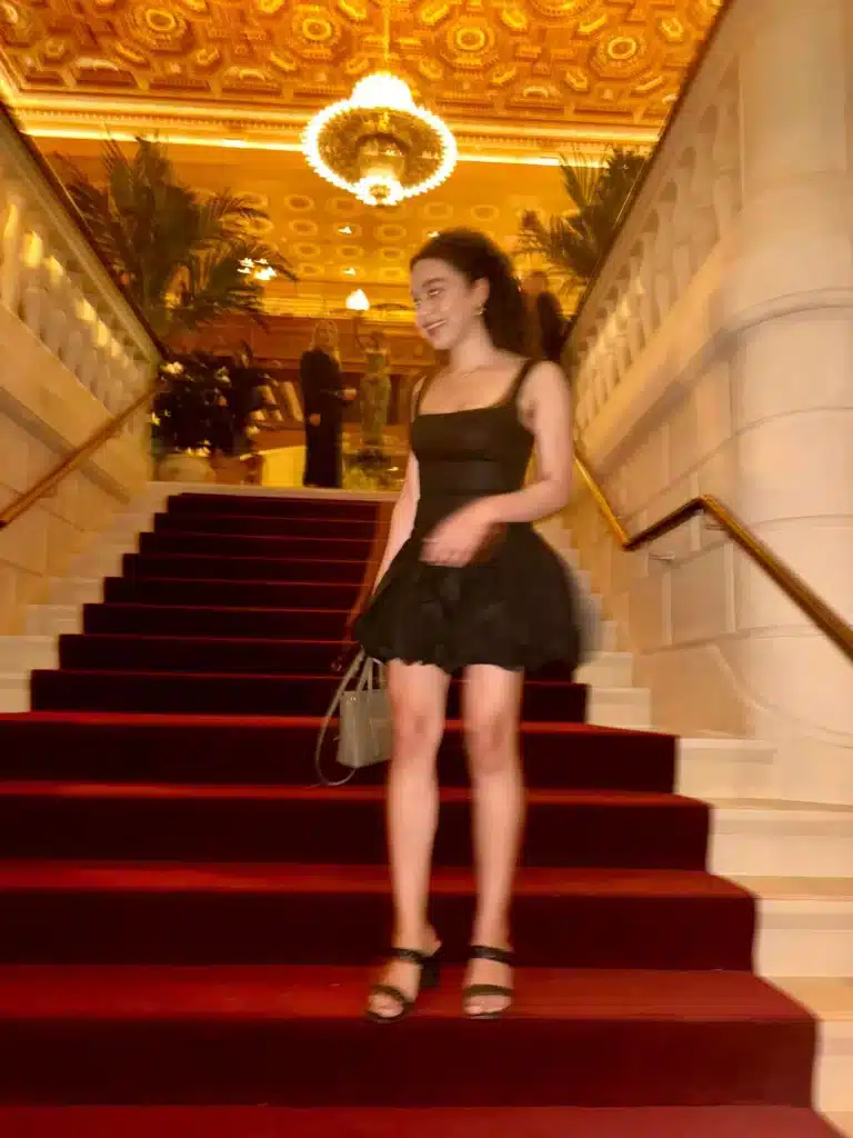 Woman in mini black reformation dress on staircase