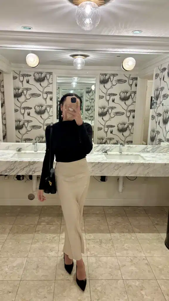 woman in elegant silk skirt and black turtleneck with black leather shoulder bag