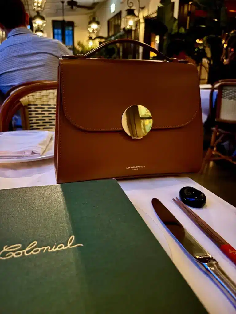 LeParmentier handbag sitting on a white tablecloth at a restaurant