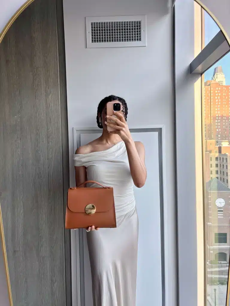 Woman in gold skirt holding a leather handbag
