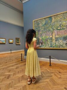 Woman looking at painting in Nuuly rented dress for nuuly vs BNTO review