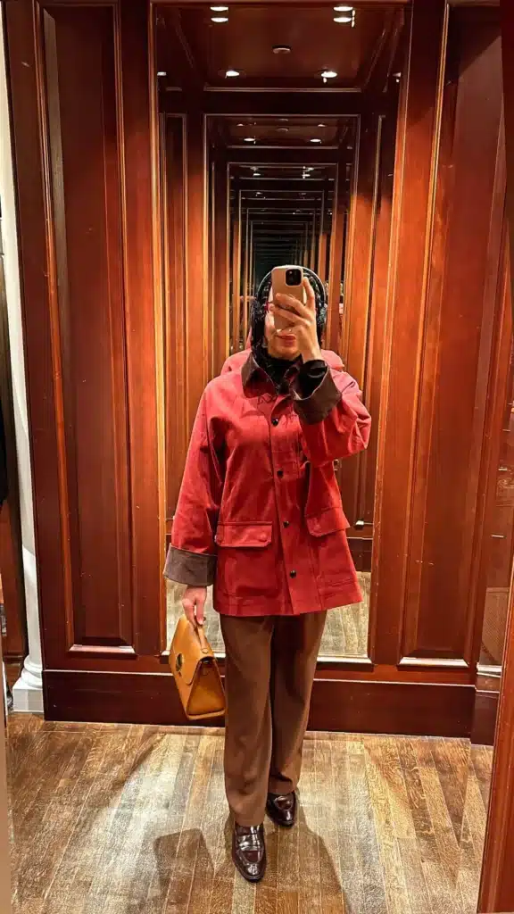 Woman in red barn jacket and trousers with loafers.