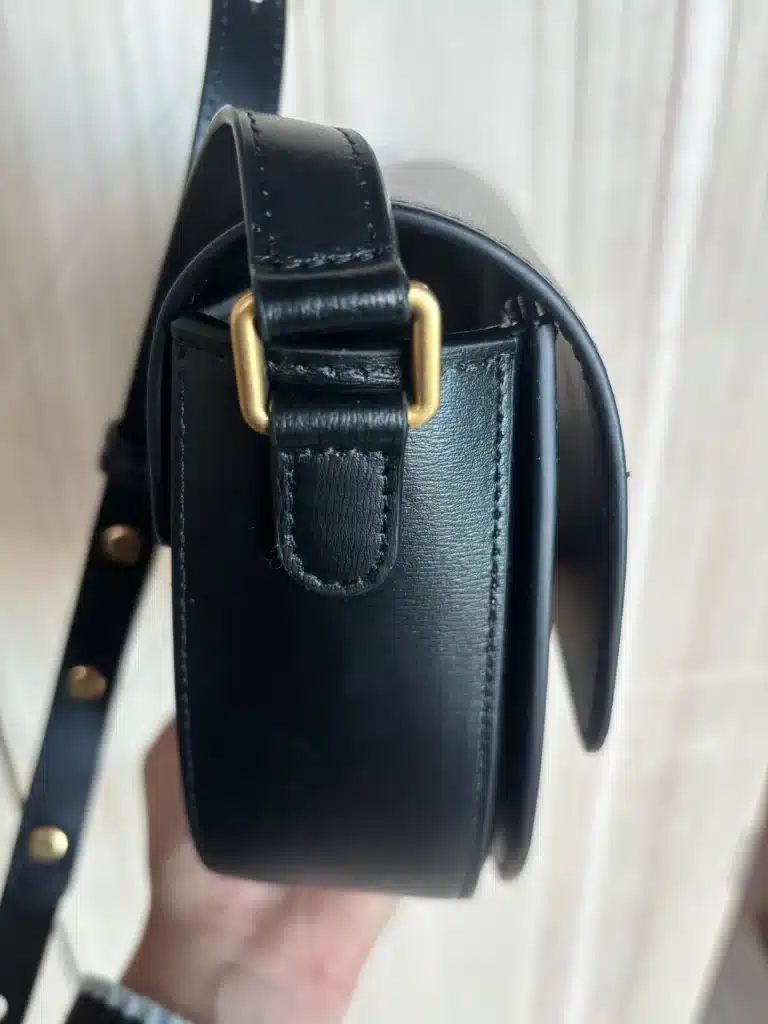 side view of a leather handbag showing gold buckle