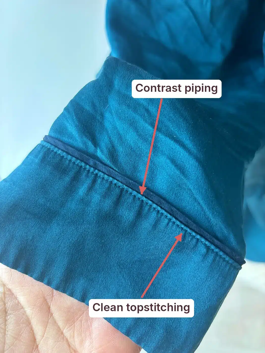 Lunya washable silk pajama cuff annotated to show contrast piping and clean topstitching