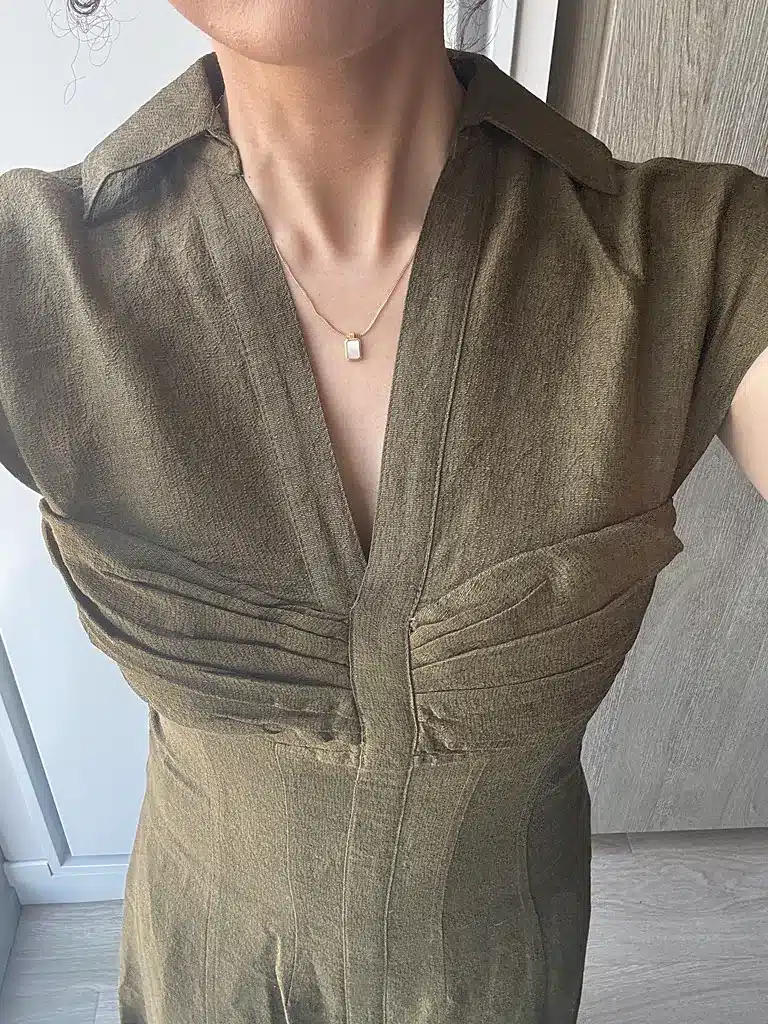 Close-up of a Cult Gaia dress bodice showing pleated bust panels, princess seams and a topstitched placket