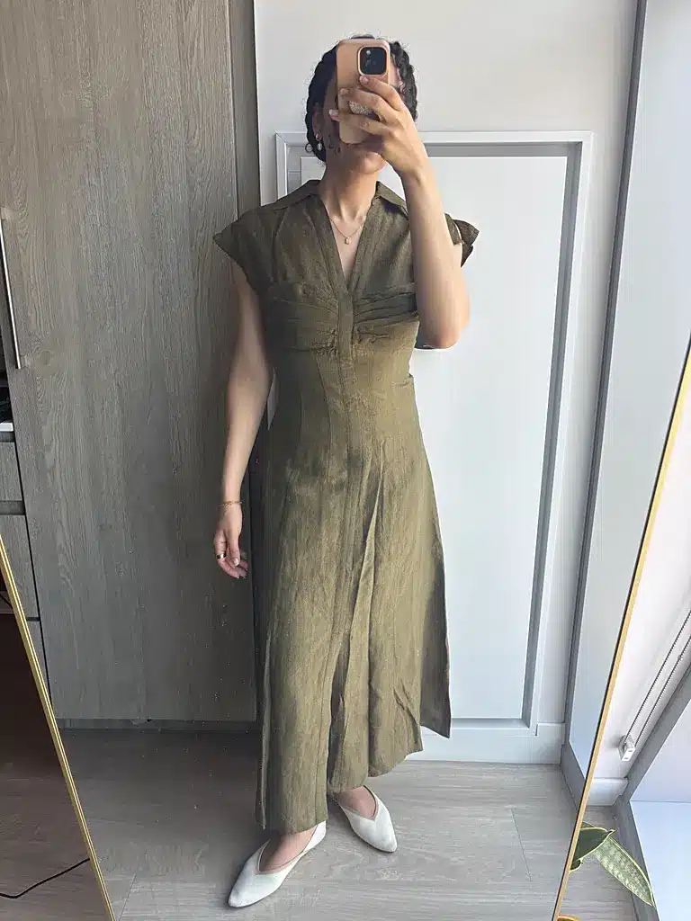 Woman wearing an olive Cult Gaia linen, wool and silk blend midi dress with white flats