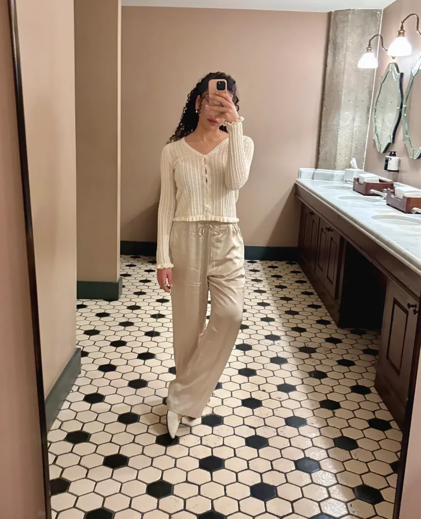 Woman wearing a cream Gap pointelle cotton cardigan with champagne Quince washable silk wide-leg pants and white flats