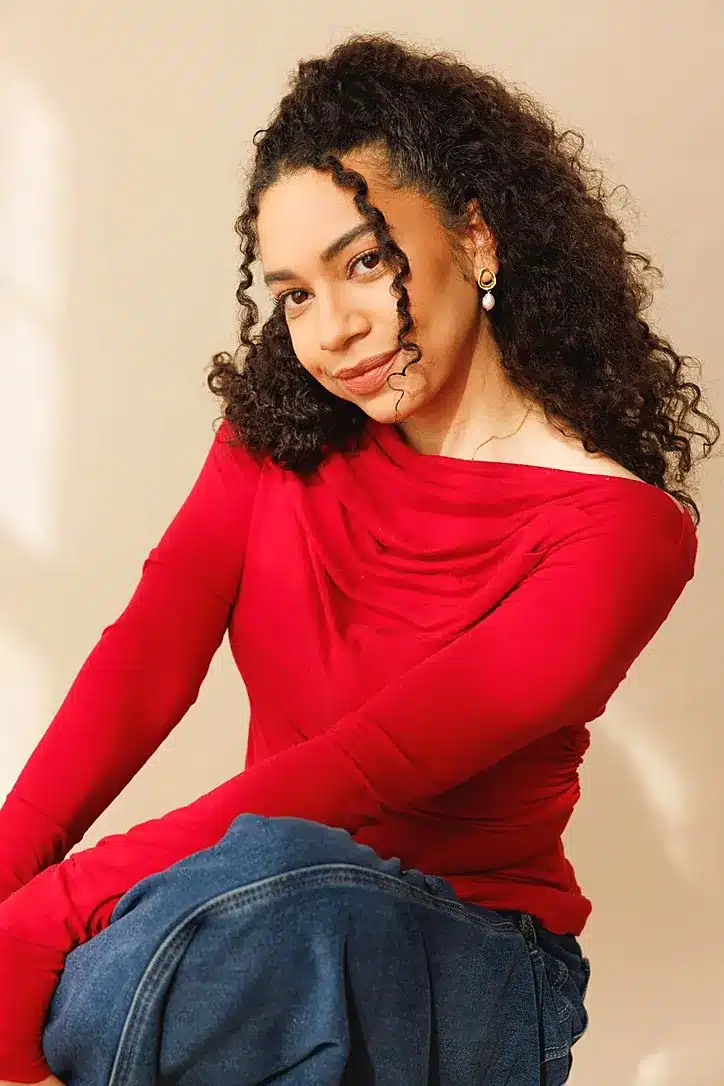 Woman in a red Marcella Cooper cowl-neck top in Tencel, paired with jeans